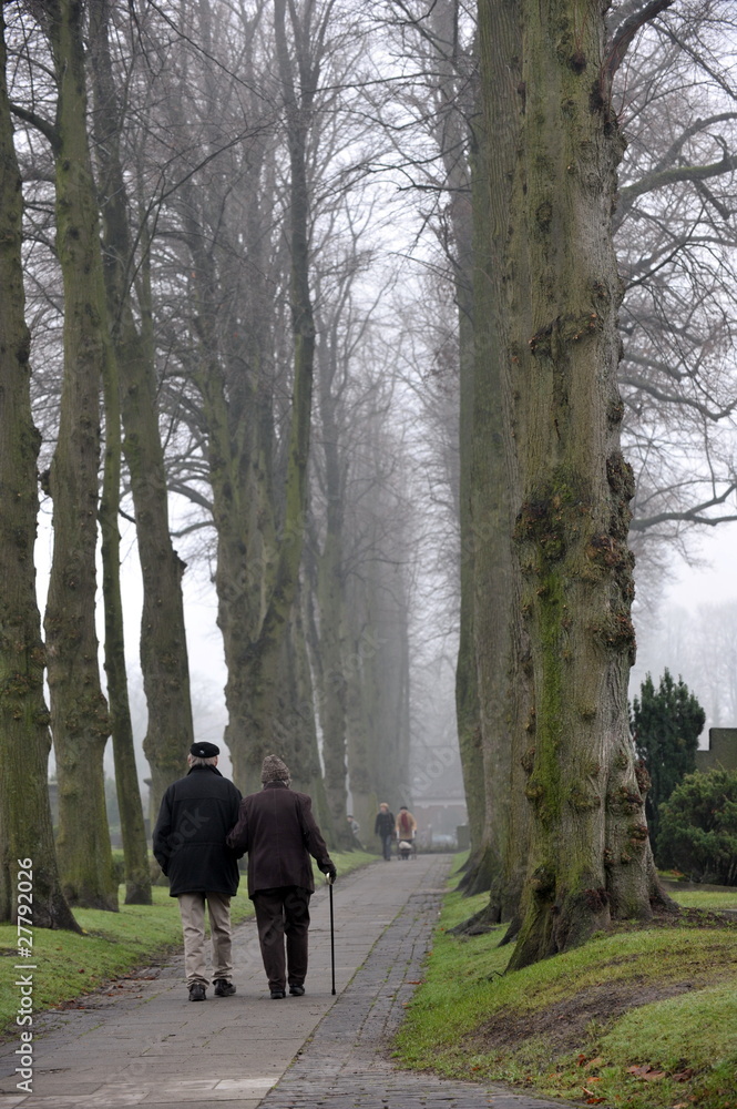 Senioren spazieren im Morgennebel auf dem herbstlichen Friedhof Senioren spazieren im Morgennebel auf dem herbstlichen Friedhof