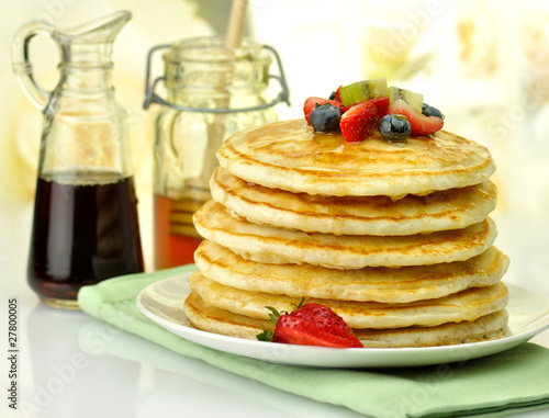 stack of pancakes with maple syrup honey and berries