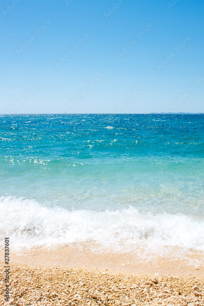beautiful pebbles beach with waves and blue sky