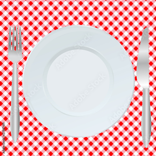 Plate, fork and spoon on red square tablecloth