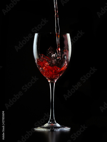 Wine is poured into a glass on a black background