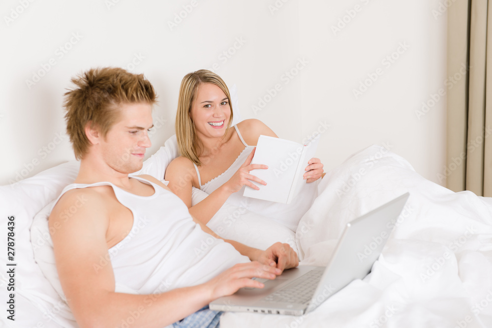 Bedroom - young couple with laptop and book Bedroom - young couple with laptop and book