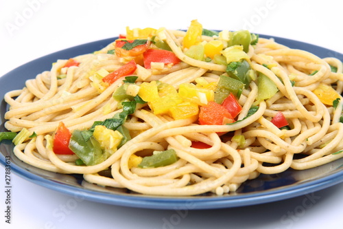 Spaghetti with vegetables on a plate in close up on white