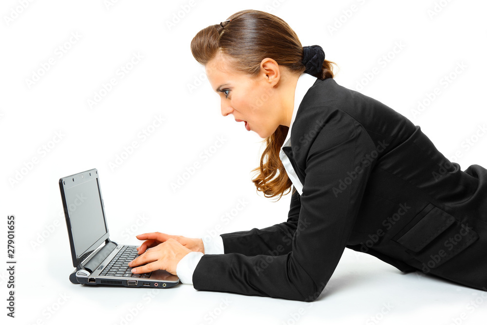 Modern business woman amazedly looks in laptops screen Modern business woman amazedly looks in laptops screen