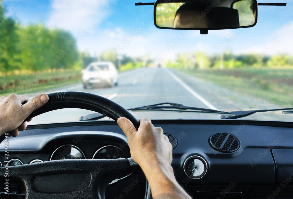 Driver's hands-on steering wheel inside of a car