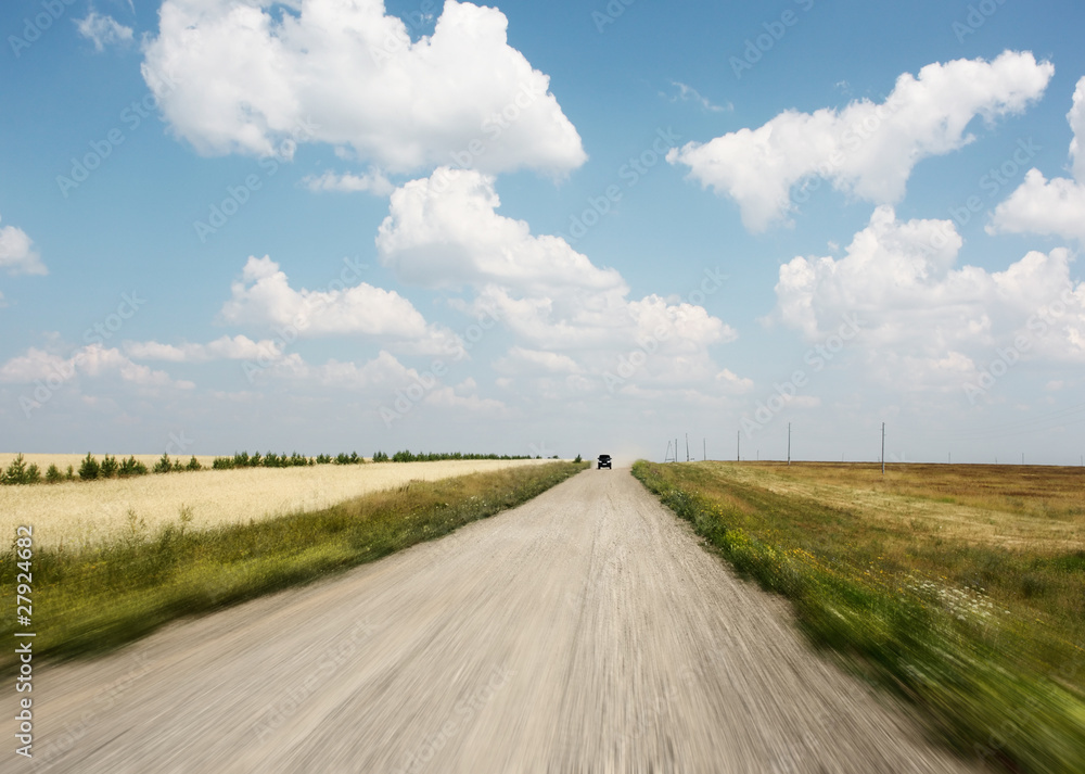 Rural motion-blurred road and blue sky with summer clouds