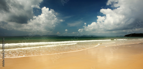 The sea with clear water yellow fine sand and sky with fluffy clouds