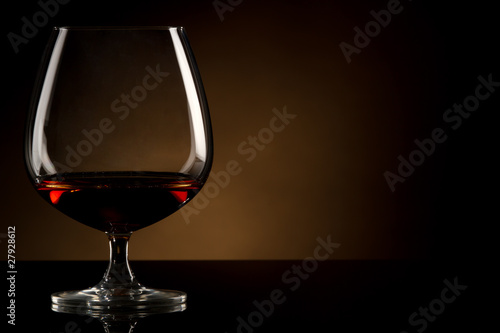 Fotografie Glass of brandy over brown background