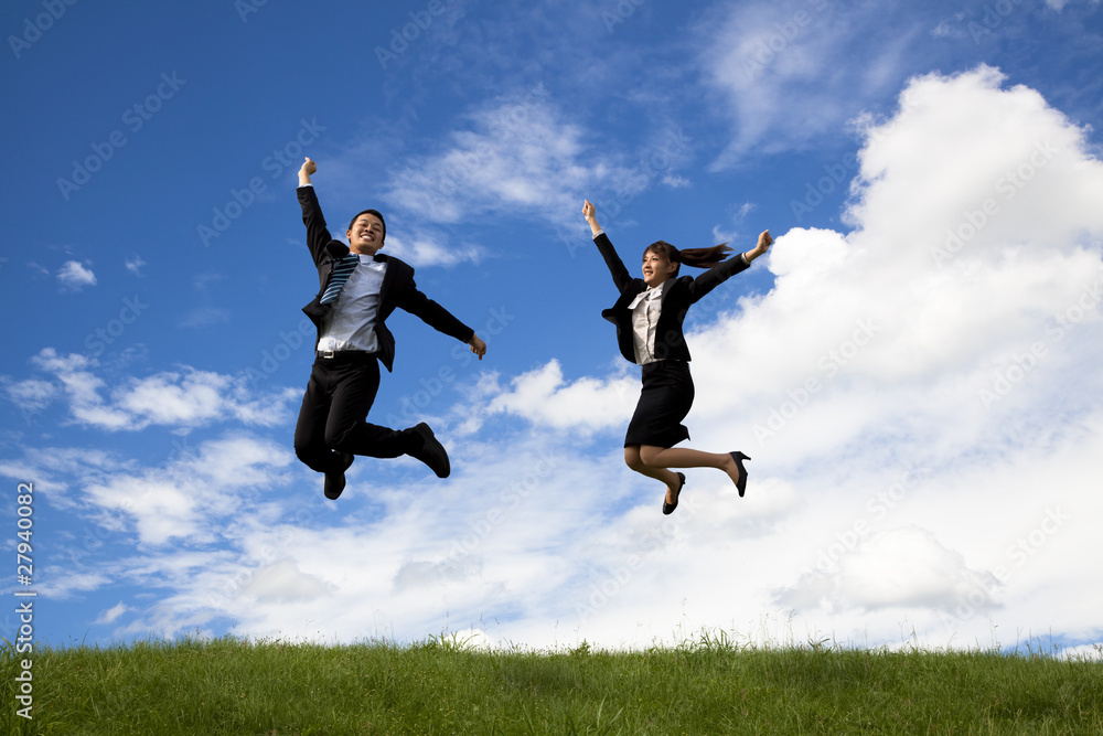 Businessman and businesswoman jumping on a green meadow . Businessman and businesswoman jumping on a green meadow .