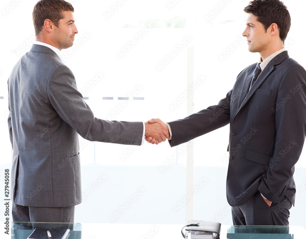 Serious businessmen shaking their hands after a meeting Serious businessmen shaking their hands after a meeting