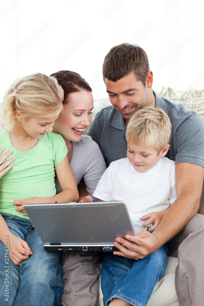 Adorable family working together on a laptop sitting on the sofa Adorable family working together on a laptop sitting on the sofa