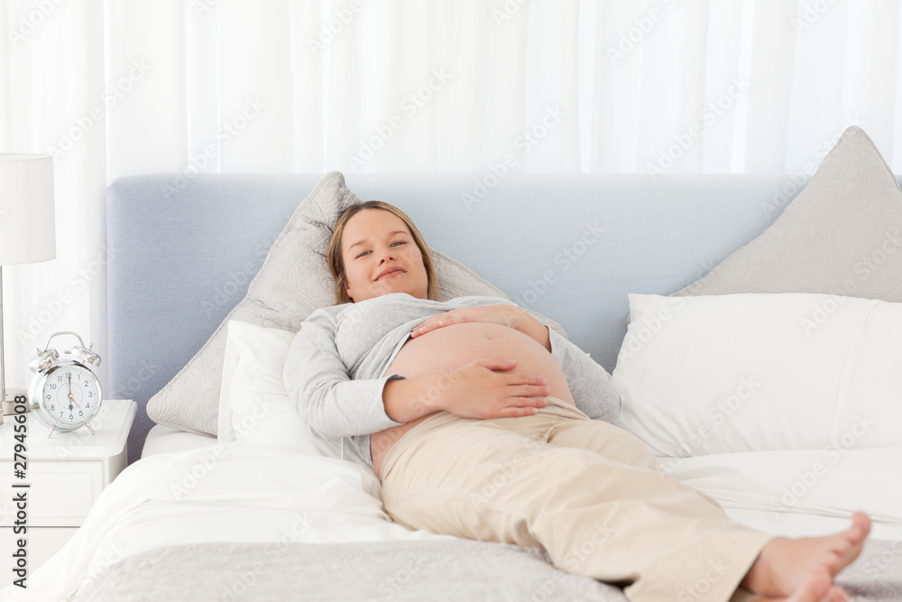 Smiling pregnant woman relaxing on a bed Smiling pregnant woman relaxing on a bed