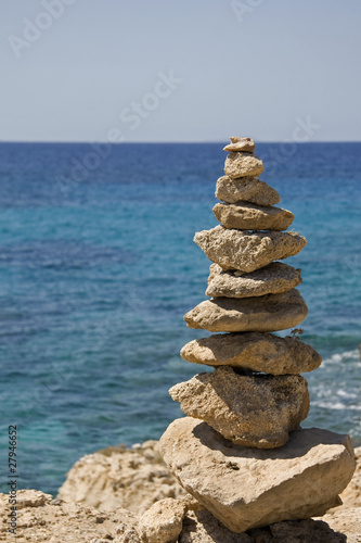 Stones balanced on cliff over sea in the background