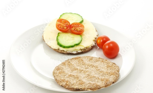 Cracker on plate, with tomato and cucumber, white background