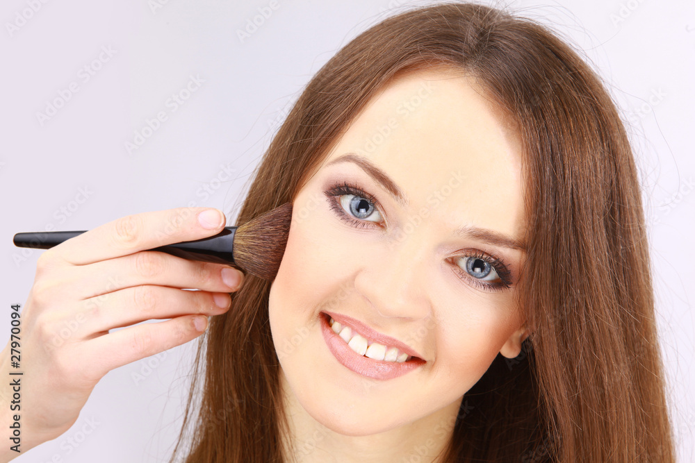 Portrait of attractive young woman applying blusher Portrait of attractive young woman applying blusher