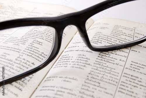 closeup of old dictionary and glasses