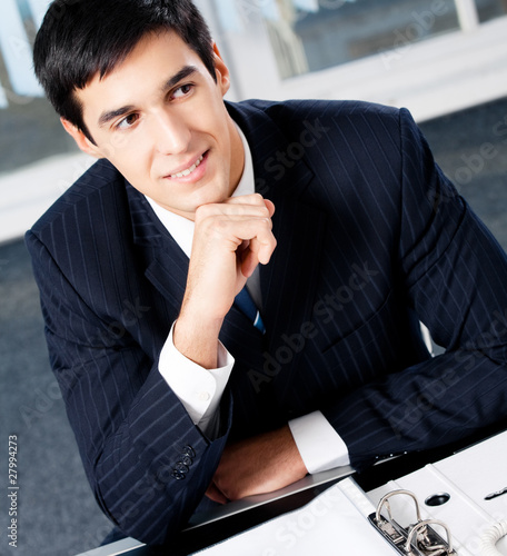 Portrait of thinkihg businessman with documents at office photo