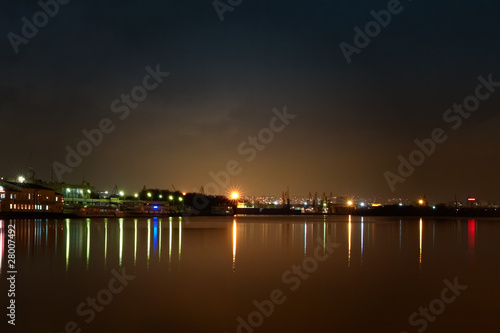City at night. Port cranes and river
