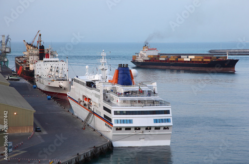 Industrial cargo ships and big white cruise liner at port photo