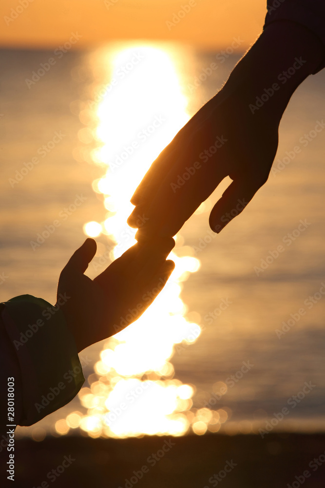 Silhouettes of two hands of child and grown man adjoin fingers