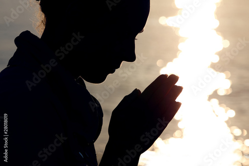 Silhouette of woman in type, which sits ashore and prays fold