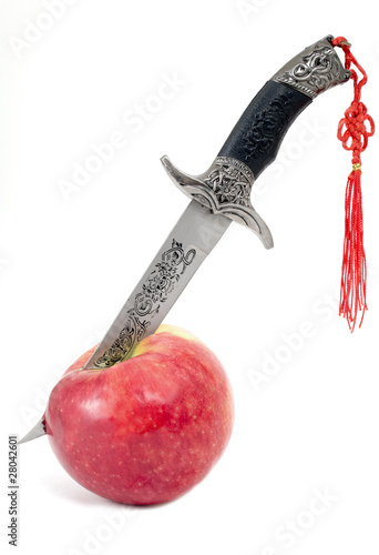 Dagger in  ripe apple on a white background