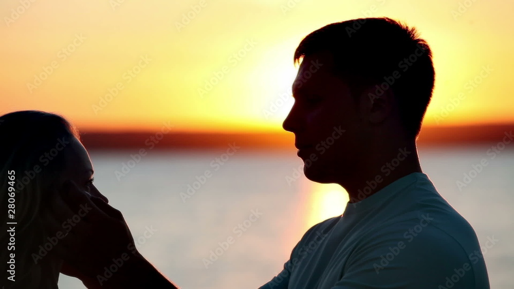 Man and woman kissing in the light of sunset Man and woman kissing in the light of sunset