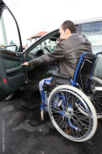 Young man in wheelchair getting in his car