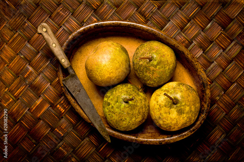 Organic pears and knife in brown bowl.