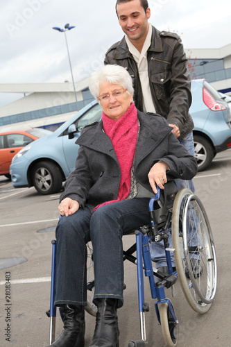 Young man assisting senior woman in wheelchair © goodluz