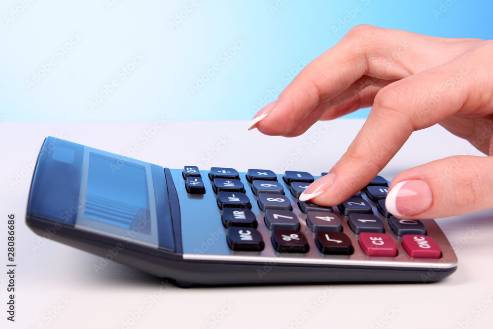 Fingers and calculator on blue background Fingers and calculator on blue background
