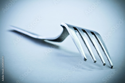 Closeup of metal fork in blue mood. Soft focus view.