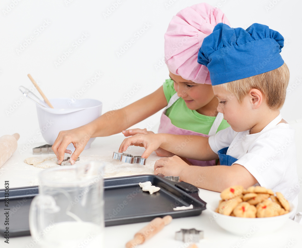 Adorable siblings cooking biscuits together in the kitchen Adorable siblings cooking biscuits together in the kitchen