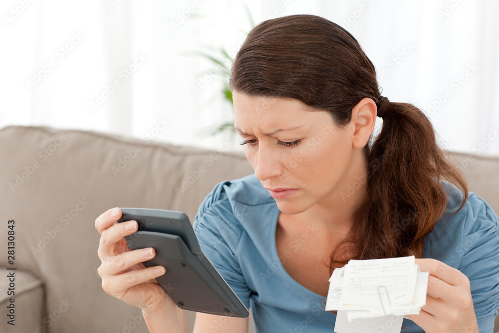 Attractive woman holding a calculator and bills while doing her Attractive woman holding a calculator and bills while doing her