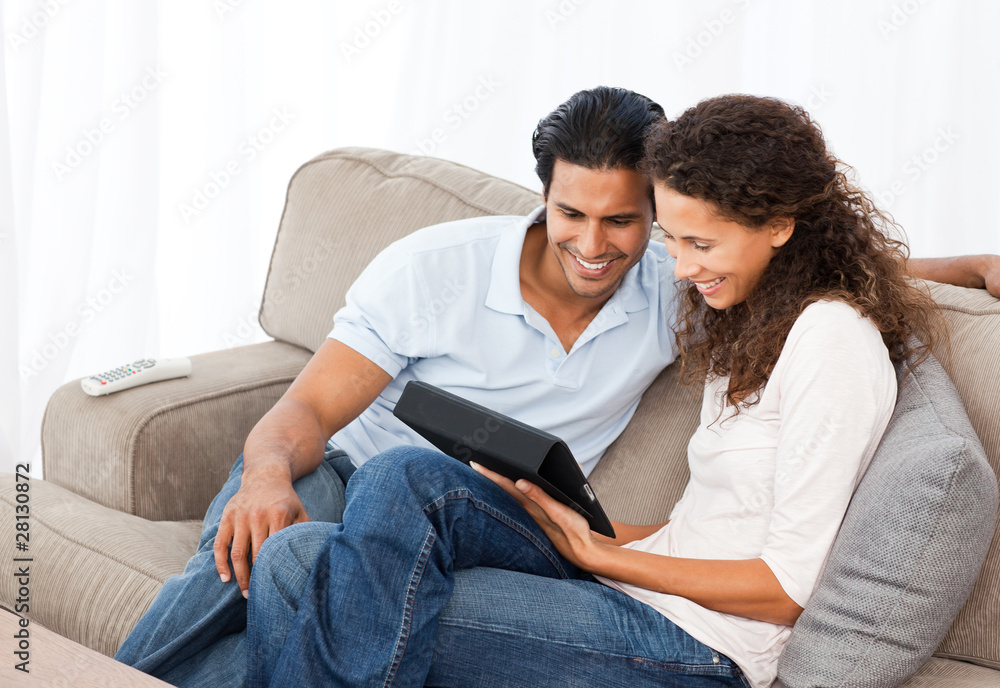 Obraz premium Lovely couple watching videos together sitting on their sofa