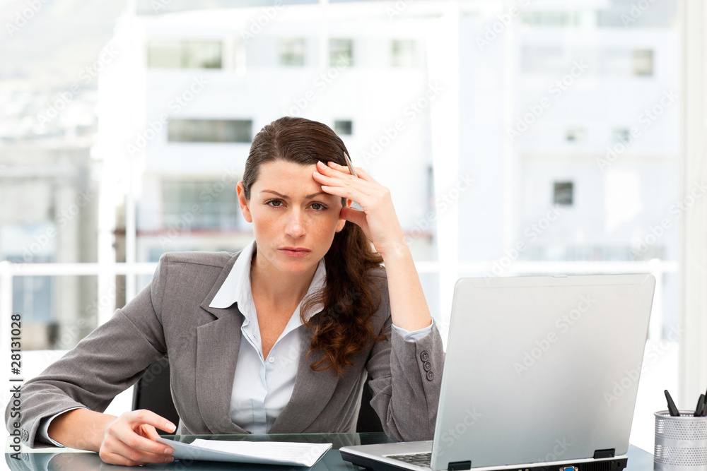 Worried businesswoman working at her desk with laptop and folder Worried businesswoman working at her desk with laptop and folder