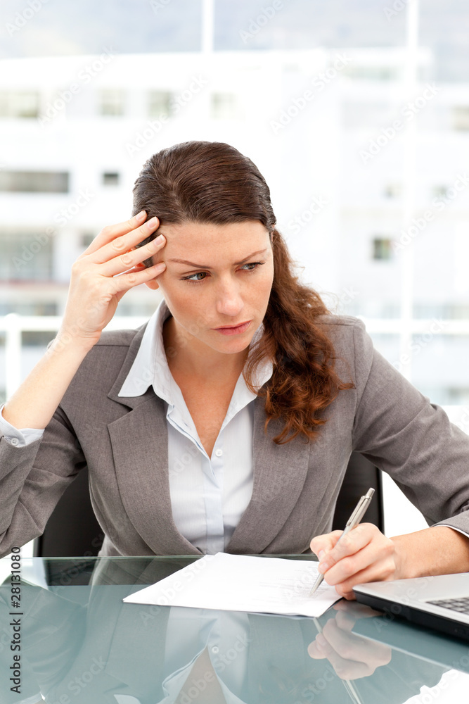 Concentrated businesswoman taking notes while working on laptop Concentrated businesswoman taking notes while working on laptop