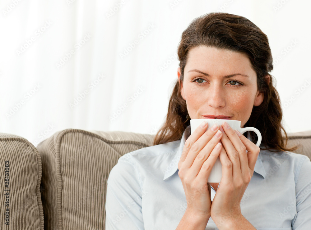 Pensive woman drinking coffee in the living room Pensive woman drinking coffee in the living room