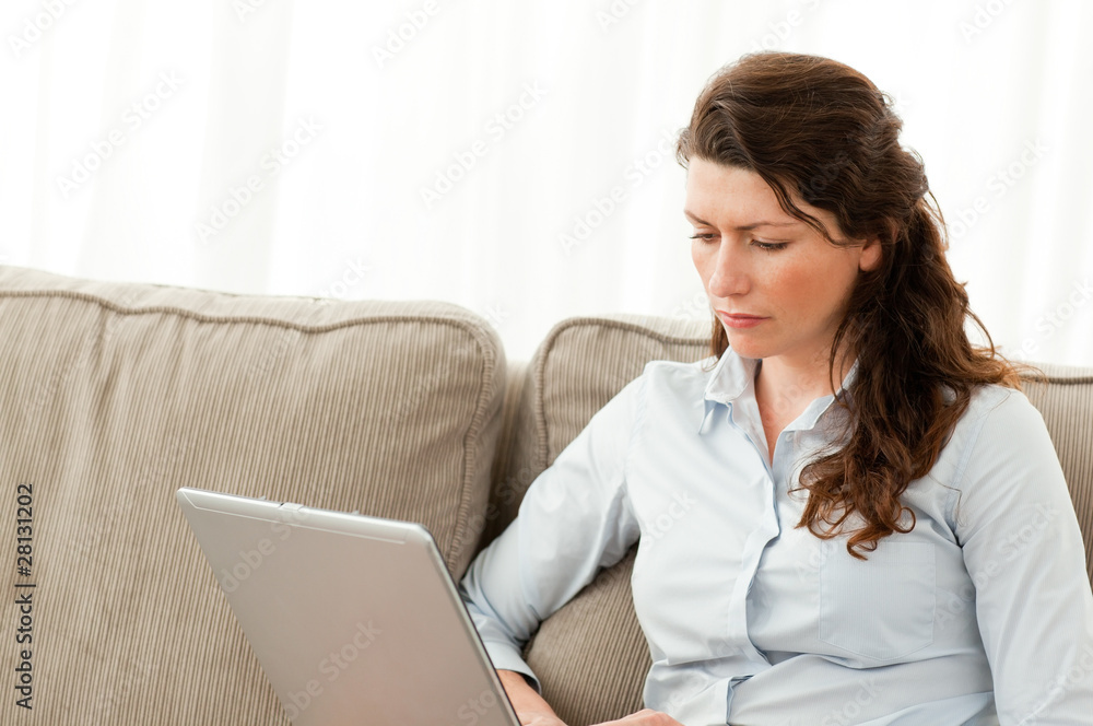 Serious businesswoman working on her laptop on the sofa Serious businesswoman working on her laptop on the sofa