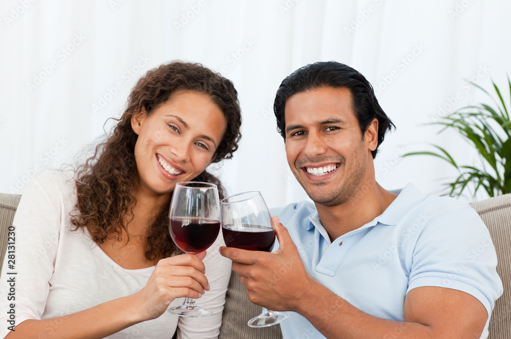 Happy couple drinking red wine sitting on the sofa Happy couple drinking red wine sitting on the sofa
