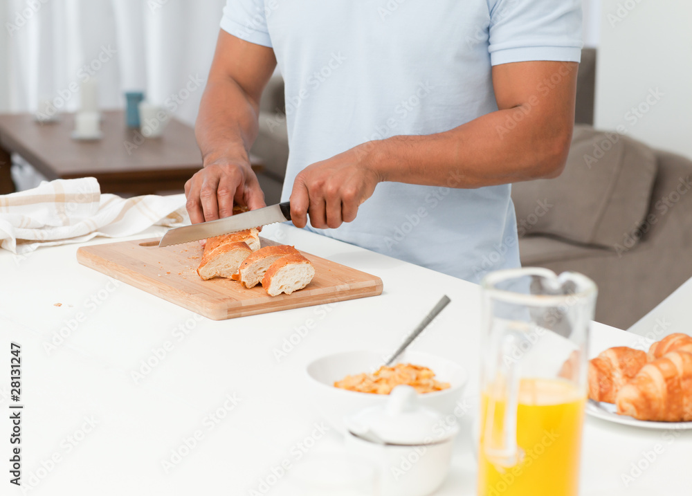 Close up of a man cutting bread during breakfast in his kitchen Close up of a man cutting bread during breakfast in his kitchen