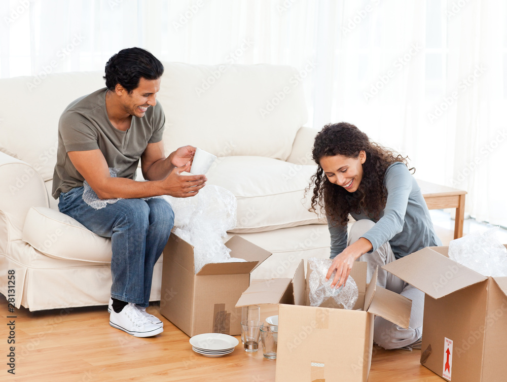 Happy couple packing glasses together in the living-room Happy couple packing glasses together in the living-room