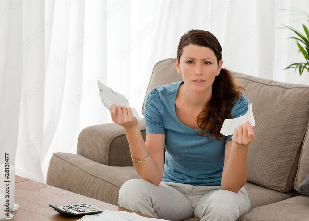 Fototapeta premium Serious woman holding bills while doing her accounts