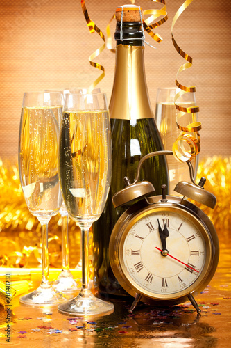 Happy New Year - Bottle of champagne, two glasses and alarm clock as a symbol of New Year's fun