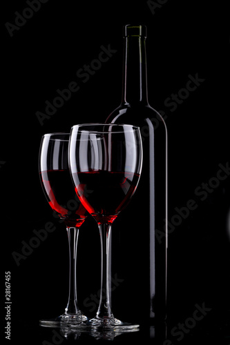 Bottle and glass of red wine on black background