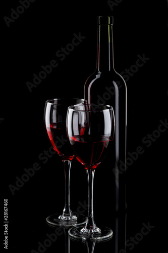 Bottle and glass of red wine on black background