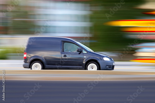 Speedy  dark minivan  is  going on road  panning and blur