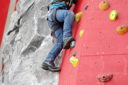 Child climbing on a wall in a climbing center photo