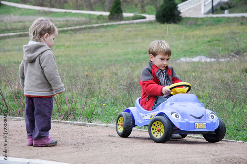 two children playing with toy car outdoors