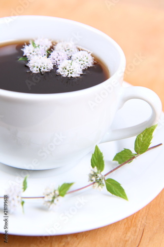 Cup of tea with mint flowers floating in it